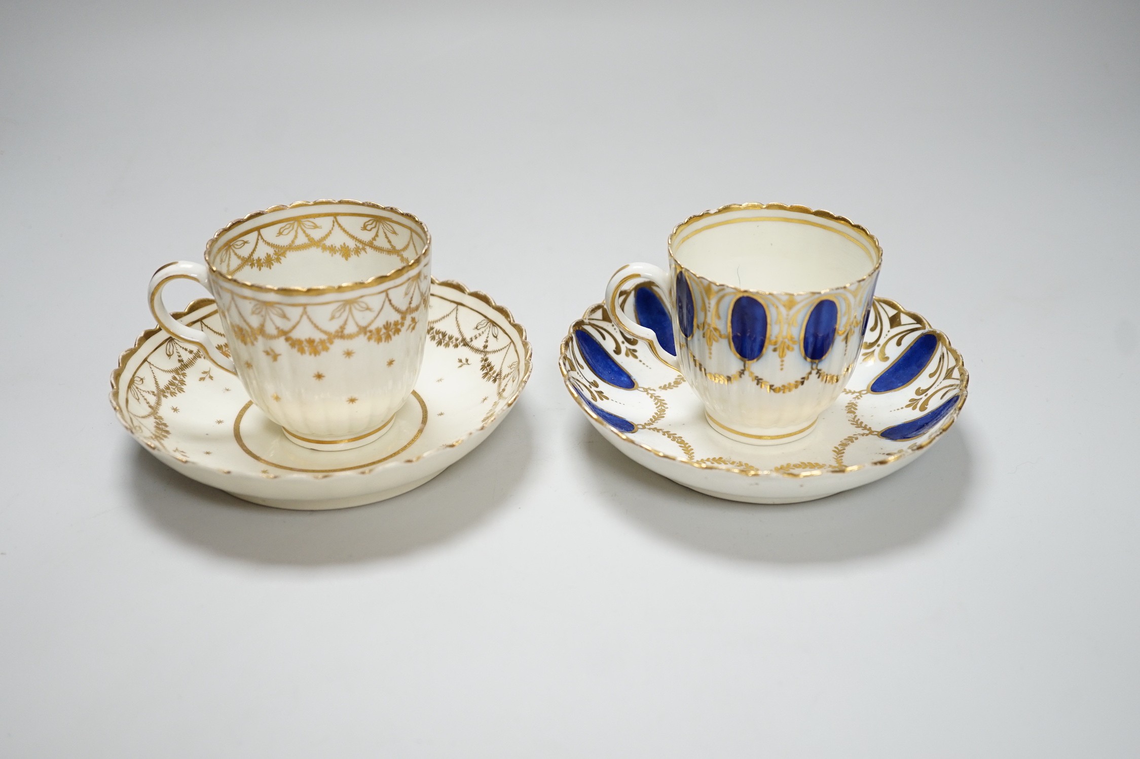 An 18th century Caughley coffee cup and saucer with blue pendants from gilt leafy swags and an 18th century Caughley coffee cup and saucer with an elaborately gilded border, both probably decorated at Chamberlains premis